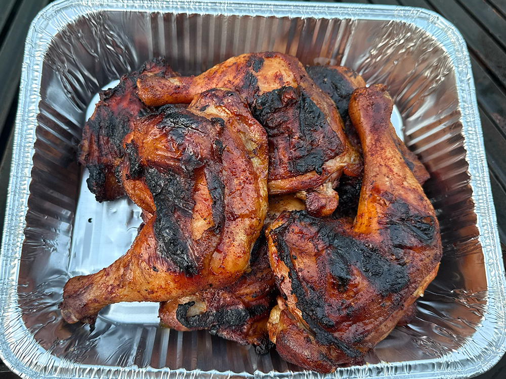 Grilled BBQ chicken quarters in a pan